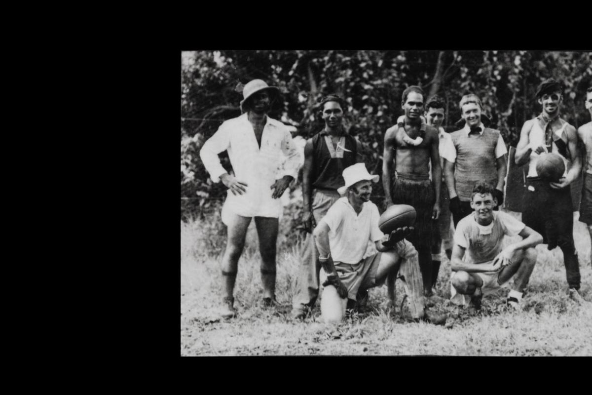 Nine men of various ethnicities, casually standing and kneeling, one holding a football and another a basketball. All wearing one or two pieces of formal wear or other fancy dress. 