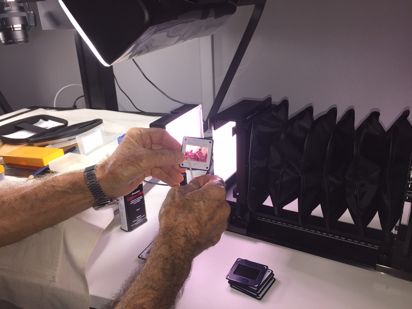 Volunteer treating a negative with a chemical and ear bud in preparation for digitisation