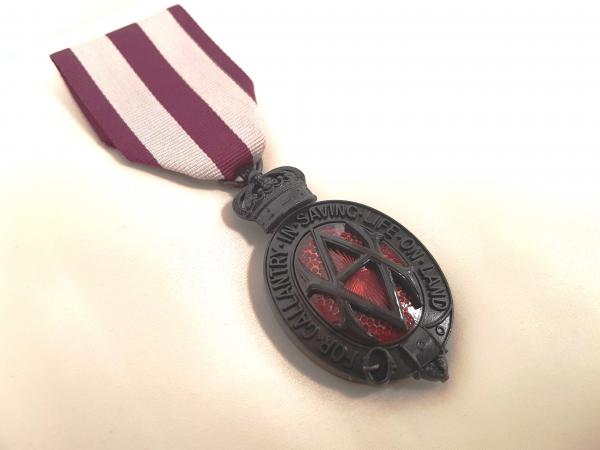 Albert medal. Ribbon is striped maroon and white. Medal is made of bronze with red embelishments